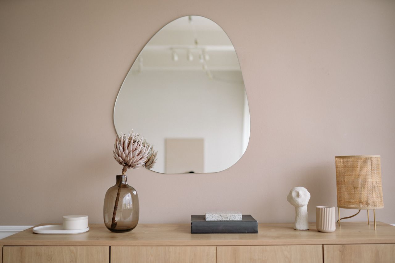 Élégant intérieur minimaliste mettant en scène un miroir, un vase décoratif et une lampe.